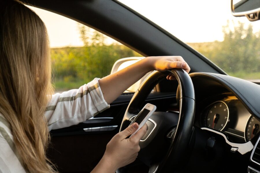 woman,sending,messages,with,smartphone,while,driving,automobile.,female,driver