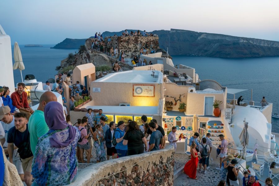 Un assembramento di persone in un locale sull'isola greca di Santorini. - © Shutterstock