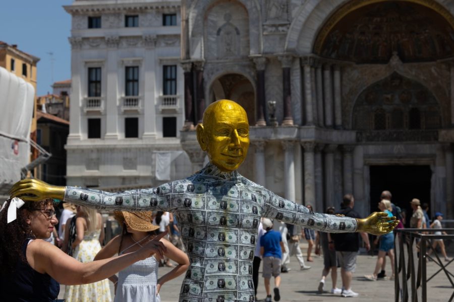 Una delle tante forme di protesta verificatesi nell'ultima settimana di giugno nella città di Venezia, teatro delle nozze tra il magnate di Amazon Jeff Bezos e la giornalista Lauren Sanchez: una statua di Bezos con il volto d'oro e il corpo ricoperto di dollari (con l'effigie dello stesso Bezos), lasciata in Piaza San Marco lo scorso 24 giugno. - © Shutterstock
